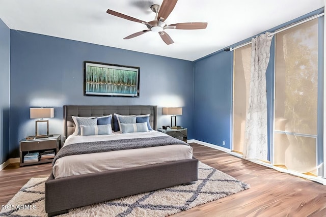 bedroom featuring wood finished floors, a ceiling fan, and baseboards