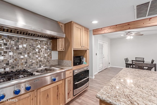 kitchen with light brown cabinets, visible vents, wall chimney range hood, appliances with stainless steel finishes, and decorative backsplash