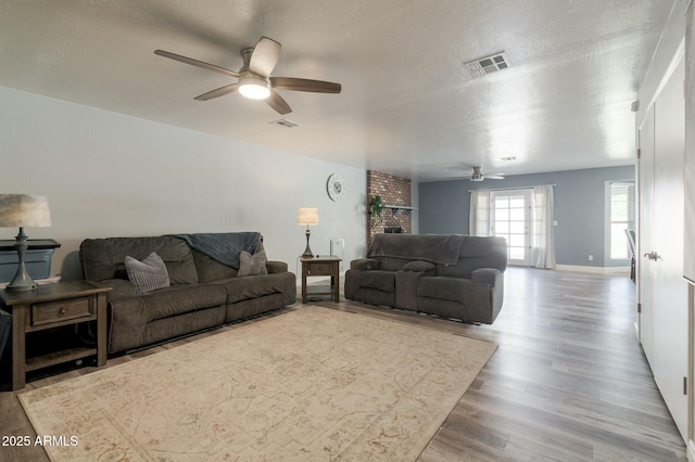 living room featuring ceiling fan, a textured ceiling, and light hardwood / wood-style flooring