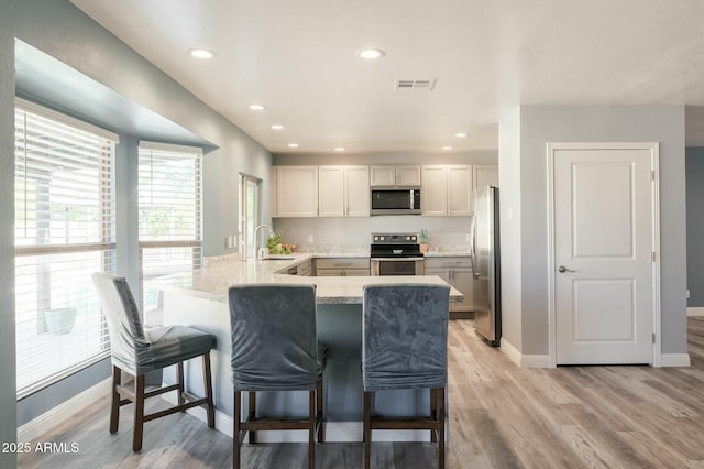 kitchen featuring white cabinetry, stainless steel appliances, kitchen peninsula, and a breakfast bar area