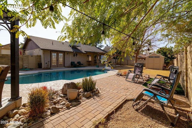 view of swimming pool with a shed, a patio area, and french doors