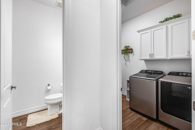 laundry room featuring cabinets, dark hardwood / wood-style flooring, and washing machine and clothes dryer