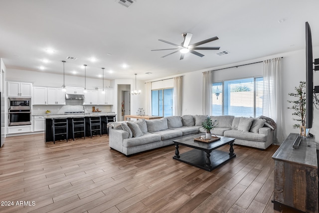 living room featuring ceiling fan with notable chandelier and hardwood / wood-style flooring