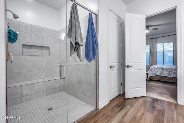 bathroom with hardwood / wood-style floors, ceiling fan, and a shower with shower door