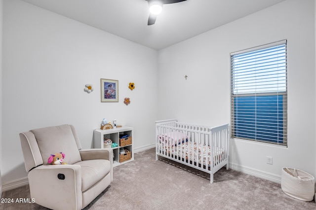 carpeted bedroom with ceiling fan and a nursery area