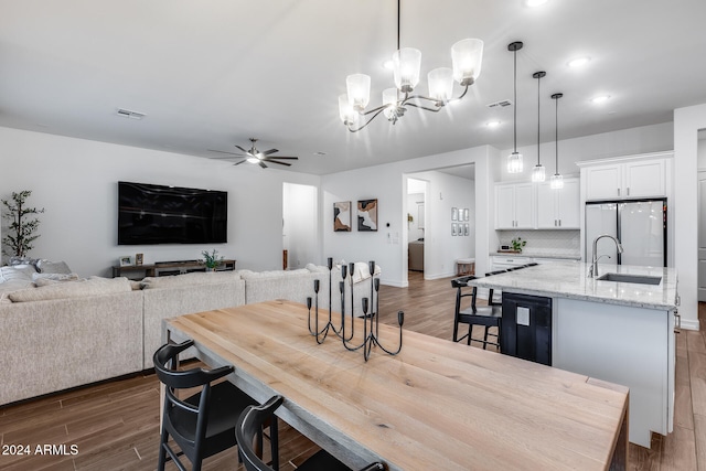 dining space with ceiling fan with notable chandelier, dark hardwood / wood-style floors, and sink