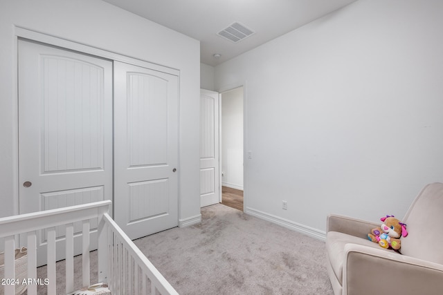 carpeted bedroom featuring a closet and a nursery area