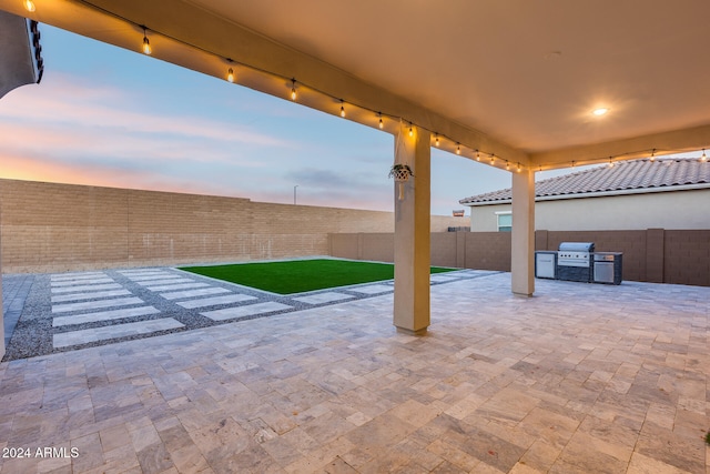 patio terrace at dusk featuring area for grilling