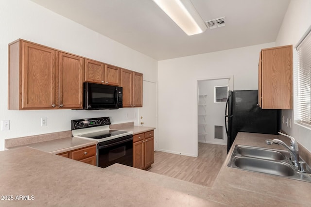 2652 E Riviera Dr, Chandler, AZ 85249 - kitchen with black appliances, a sink, light wood finished floors, light countertops, and brown cabinets