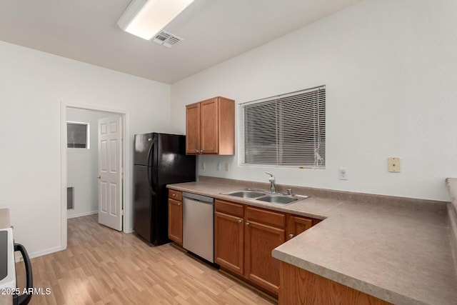 2652 E Riviera Dr, Chandler, AZ 85249 - kitchen with dishwasher, freestanding refrigerator, a sink, light wood finished floors, and brown cabinetry