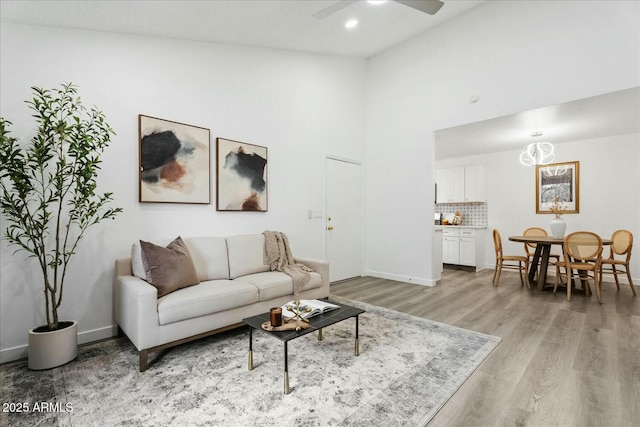 living room with ceiling fan, high vaulted ceiling, and light wood-type flooring