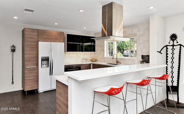 kitchen with dark tile patterned flooring, black oven, island exhaust hood, a sink, and fridge with ice dispenser