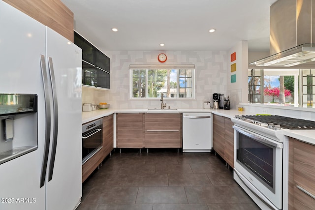 kitchen with dark tile patterned flooring, modern cabinets, a sink, range hood, and white appliances