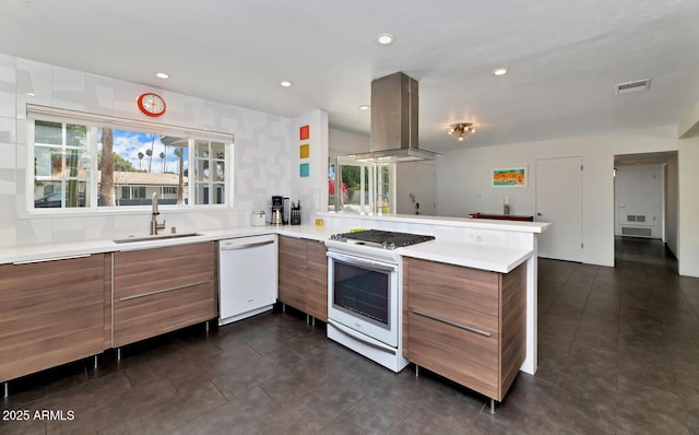 kitchen featuring visible vents, modern cabinets, a sink, white appliances, and island range hood