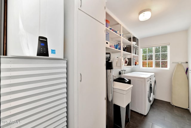 washroom with independent washer and dryer, dark tile patterned floors, and laundry area