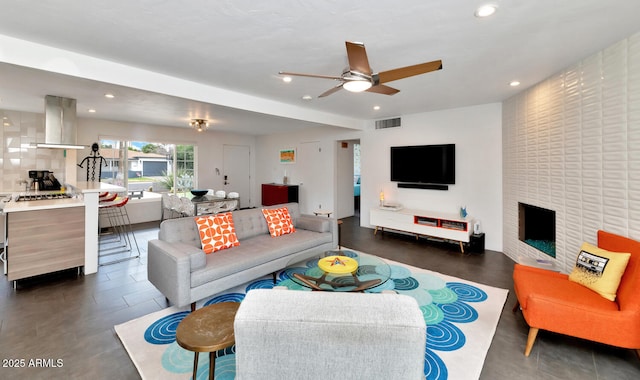 living room featuring ceiling fan, recessed lighting, visible vents, and a large fireplace