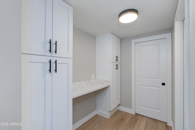 interior space with baseboards, light wood-style flooring, and built in desk