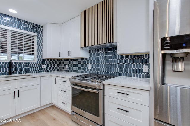 kitchen with backsplash, white cabinetry, stainless steel appliances, and a sink