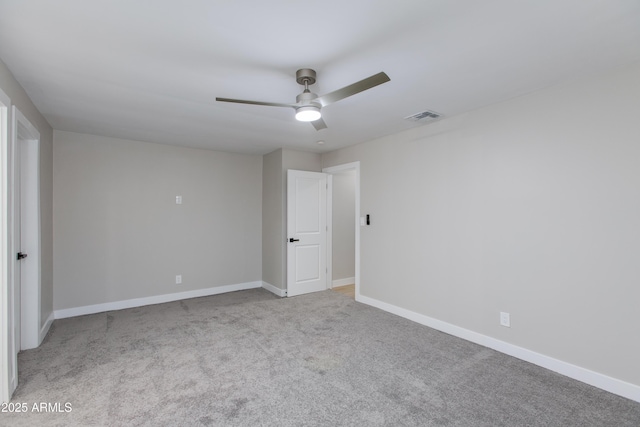 carpeted empty room featuring visible vents, a ceiling fan, and baseboards