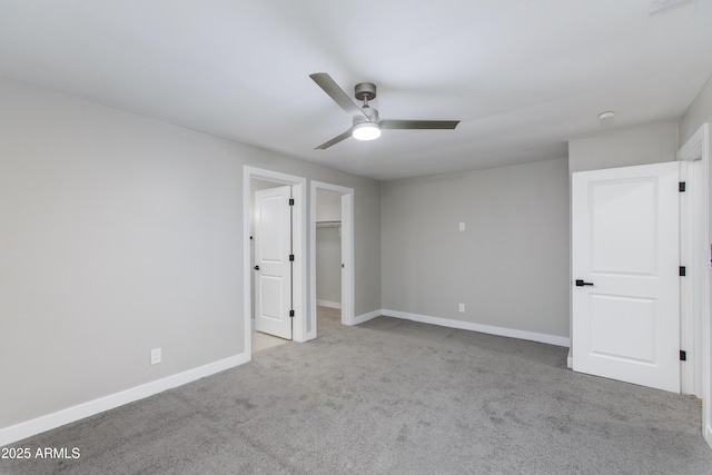 unfurnished bedroom with a spacious closet, carpet flooring, a ceiling fan, and baseboards