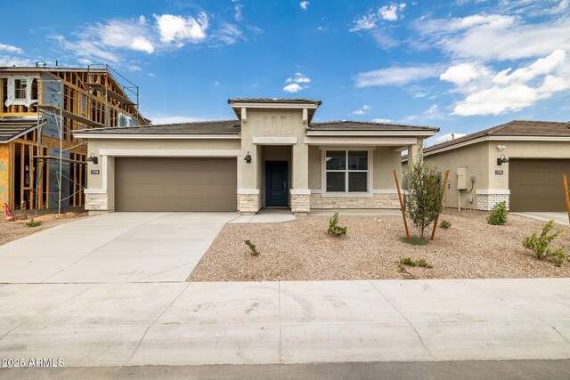 17746 W Turquoise Ave, Waddell, AZ 85355 - prairie-style house with stucco siding, an attached garage, stone siding, driveway, and a tile roof