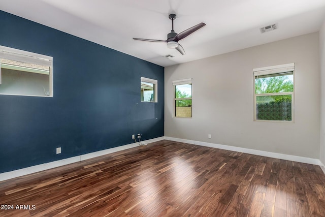 spare room with ceiling fan, plenty of natural light, and dark wood-type flooring