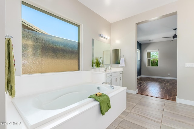 bathroom with hardwood / wood-style floors, vanity, ceiling fan, and a tub