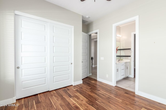 unfurnished bedroom with ensuite bathroom, dark wood-type flooring, and a closet