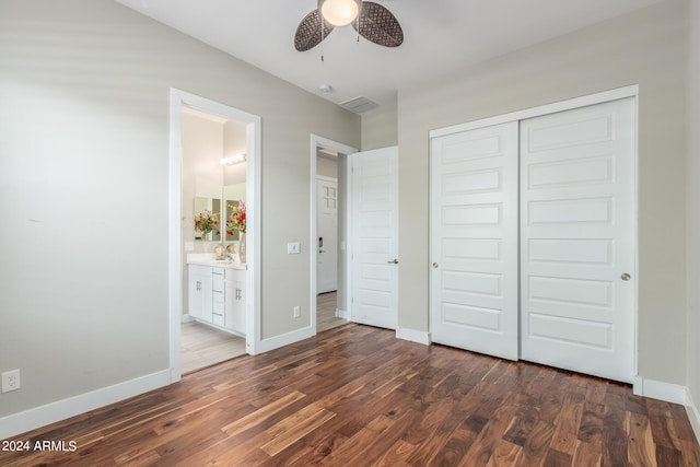 unfurnished bedroom with connected bathroom, ceiling fan, a closet, and dark wood-type flooring