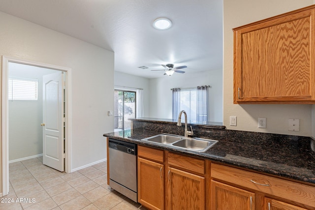 kitchen featuring sink, light tile patterned flooring, ceiling fan, stainless steel dishwasher, and dark stone counters