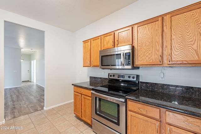 kitchen featuring appliances with stainless steel finishes, dark stone countertops, and light tile patterned floors