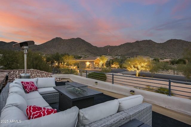 patio terrace at dusk with outdoor lounge area, a mountain view, and a balcony