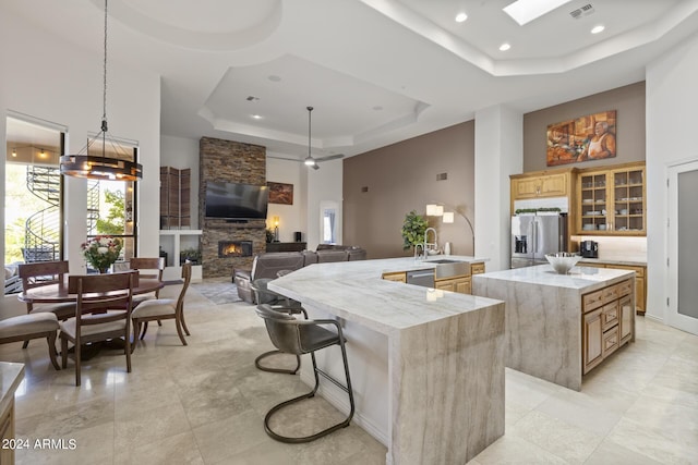 kitchen featuring a skylight, stainless steel appliances, a raised ceiling, decorative light fixtures, and a kitchen island