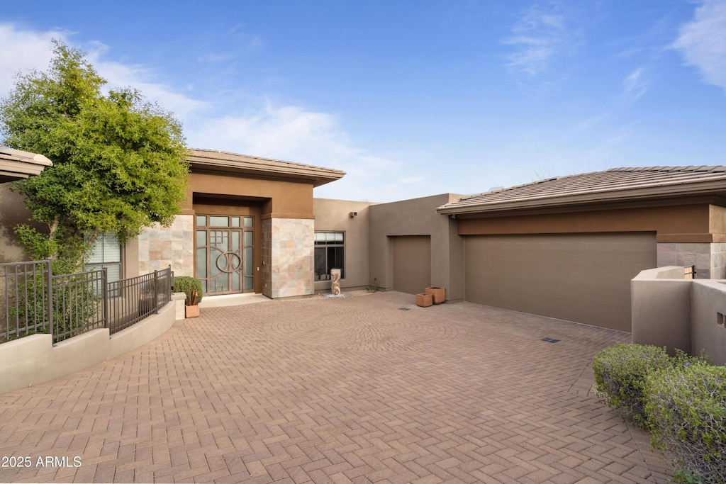 view of front of property featuring a tiled roof, decorative driveway, an attached garage, and stucco siding