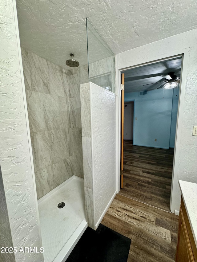 bathroom featuring tiled shower, wood-type flooring, and a textured ceiling