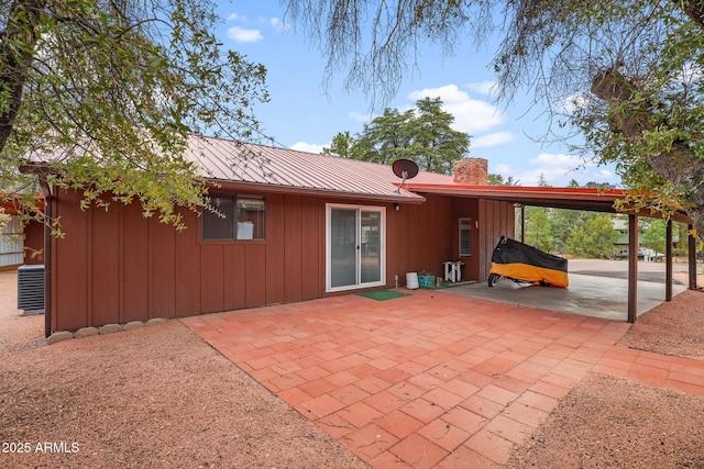 rear view of house with cooling unit, a carport, and a patio