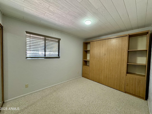 unfurnished bedroom with light colored carpet, wood ceiling, and a closet