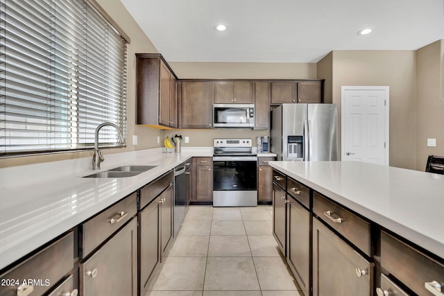 kitchen featuring appliances with stainless steel finishes, dark brown cabinets, sink, and light tile patterned floors