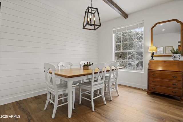 dining room with beamed ceiling, baseboards, and wood finished floors