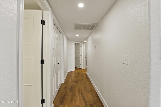 hall featuring baseboards, visible vents, dark wood-type flooring, and recessed lighting