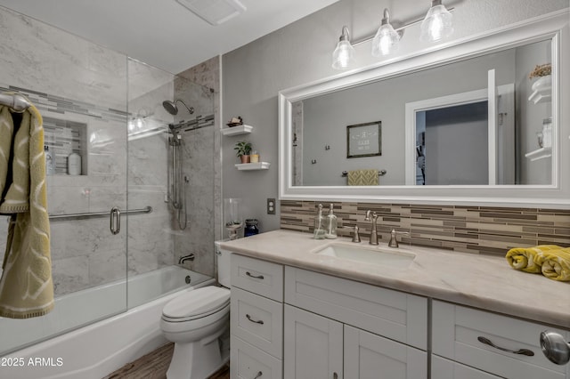 full bathroom with vanity, toilet, backsplash, and bath / shower combo with glass door