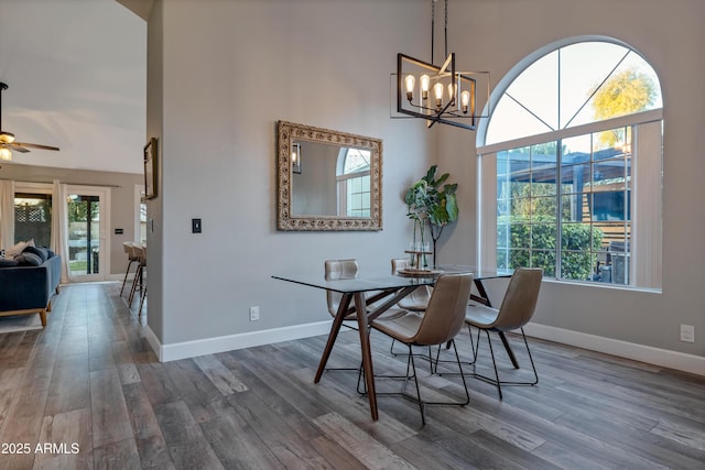 dining area featuring dark hardwood / wood-style flooring, a wealth of natural light, and a high ceiling