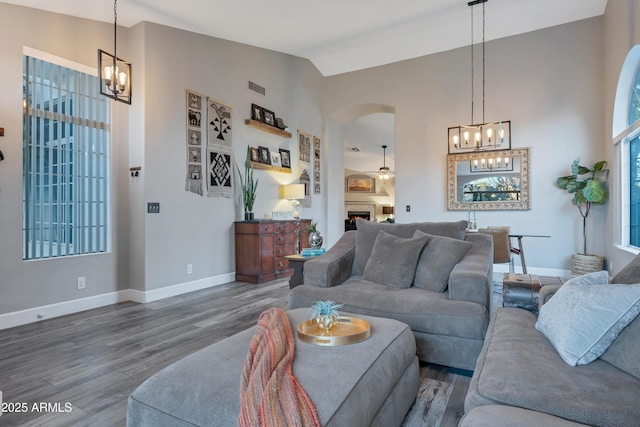 living room with wood-type flooring, vaulted ceiling, and a notable chandelier