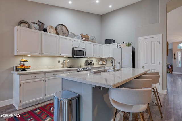 kitchen featuring appliances with stainless steel finishes, a breakfast bar, a center island with sink, and white cabinets