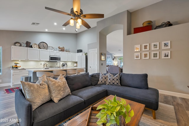 living room featuring ceiling fan, wood-type flooring, sink, and high vaulted ceiling