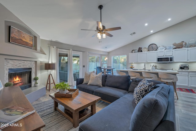 living room with ceiling fan, high vaulted ceiling, and light hardwood / wood-style floors