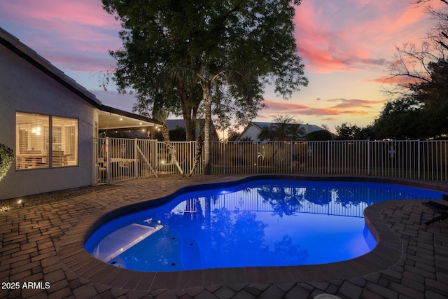 pool at dusk featuring a patio