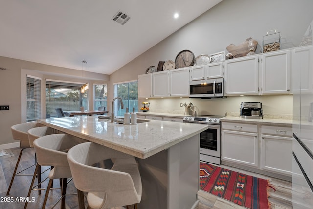 kitchen with white cabinetry, appliances with stainless steel finishes, an island with sink, and pendant lighting