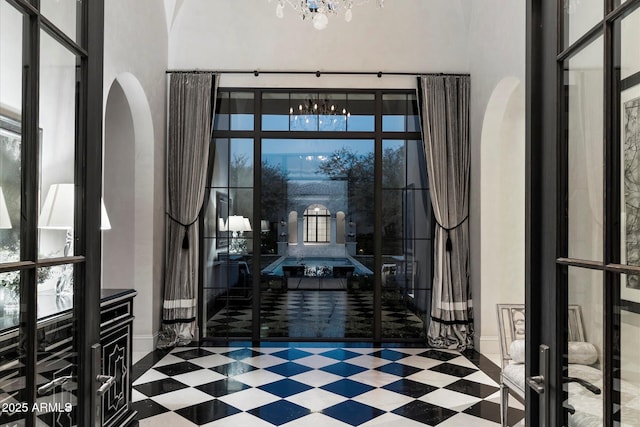 foyer featuring plenty of natural light, a notable chandelier, arched walkways, and tile patterned floors