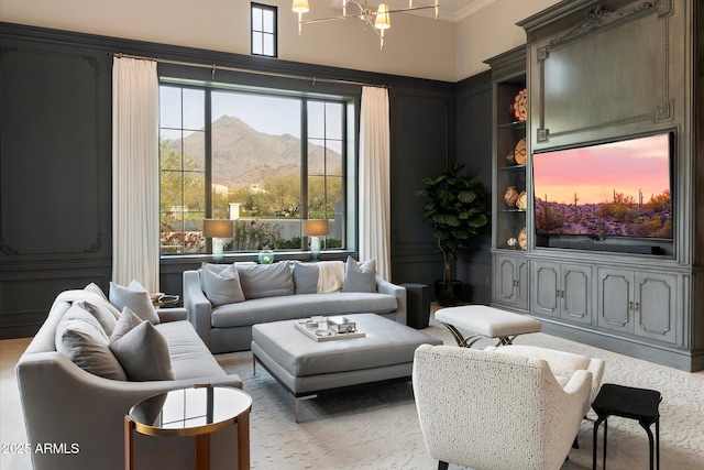 living area featuring built in features, crown molding, and a notable chandelier